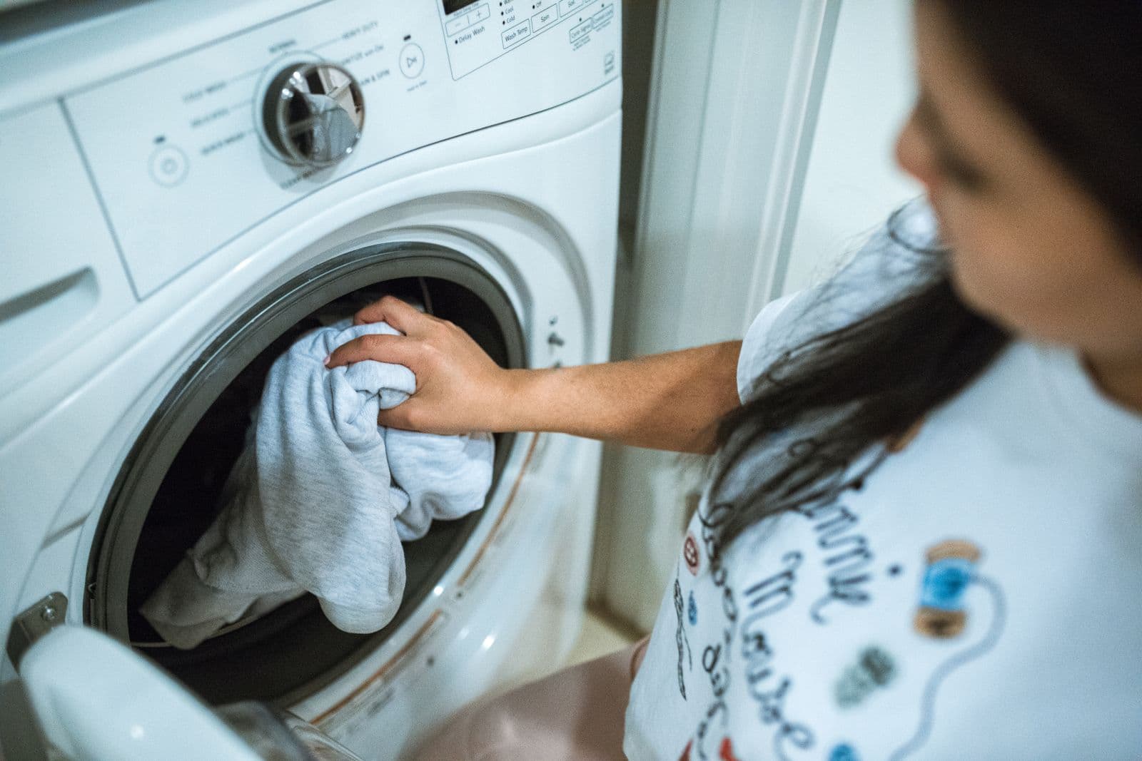 Person loading laundry into a washing machine at home